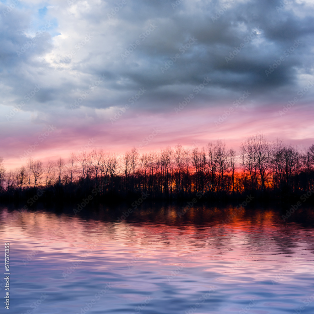 Obraz premium dramatic sunset over the forest silhouette reflected in a lake