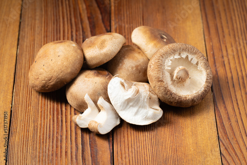 Multiple fresh shiitake mushrooms on wooden board