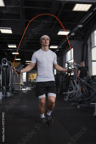 Vertical full length shot of a sportsman exerising on jumping rope