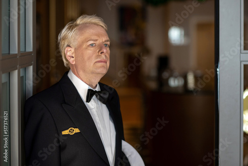 Ein deutscher Marinesoldat steht in seinen Gesellschaftsanzug gekleidet an der Tür eines Restaurants und beobachtet mit hoheitlichem Blick die Szenerie photo