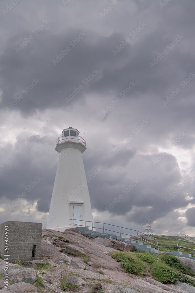 The lighthouse at Cape Spear, Newfoundland, the easternmost point in North America, is seen under a dark cloudy sky.