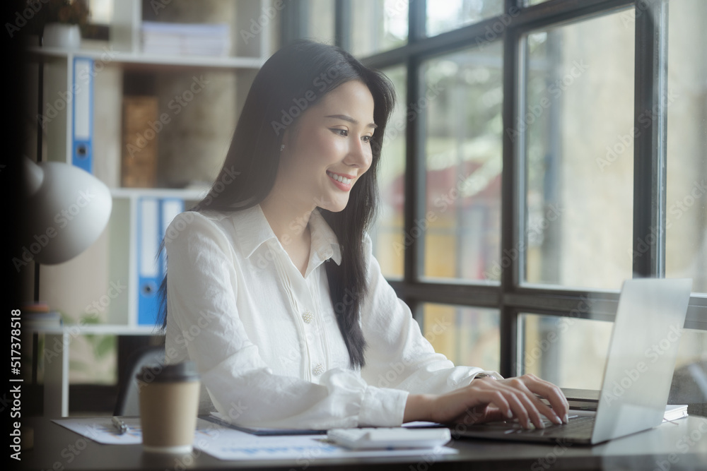 An Asian female employee sits in the office of the marketing department of a startup company, she is a marketing, customer liaison and consulting worker. Marketing concept. An Asian female employee sits in the office of the marketing department of a startup company, she is a marketing, customer liaison and consulting worker. Marketing concept.