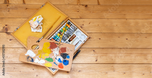 The set of oil paints with a palette on a plank floor