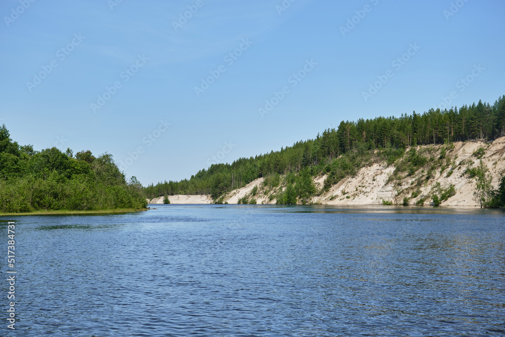 Blue lake and green mixed forest on a sunny summer day. Girvas paleovolcano is popular place among tourists. The concept of travel in Russia.