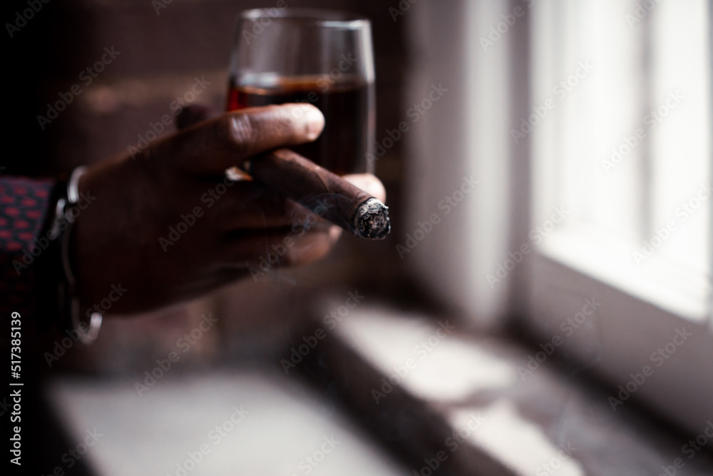man holding cigar and glass