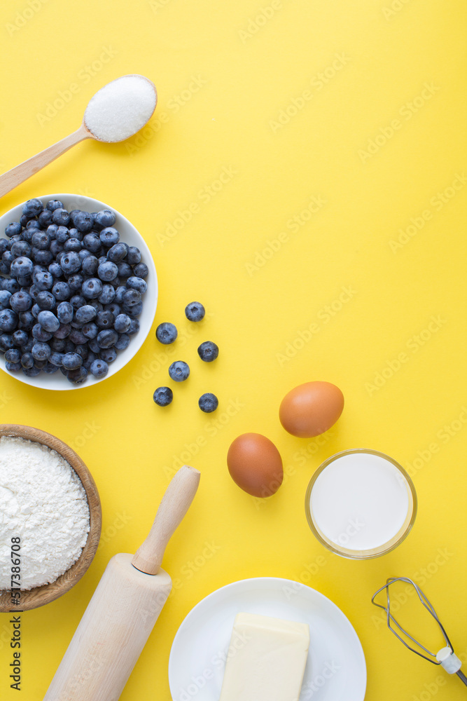 Top view of ingredients for making blueberry pie or cake on the yellow background. Copy space. Location vertical. Top view of ingredients for making blueberry pie or cake on the yellow background. Copy space. Location vertical.