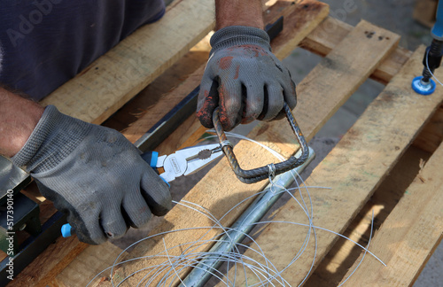 Close up photo of man holding pliers. Man works with reinforcement steel. Construction work in details. 