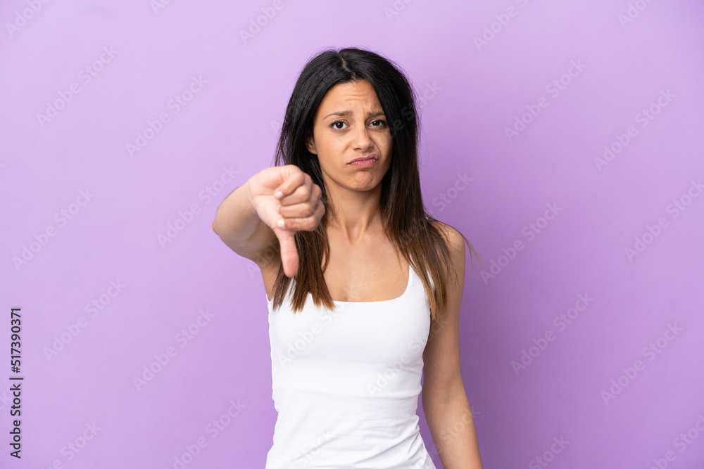 Young caucasian woman isolated on purple background showing thumb down with negative expression Young caucasian woman isolated on purple background showing thumb down with negative expression