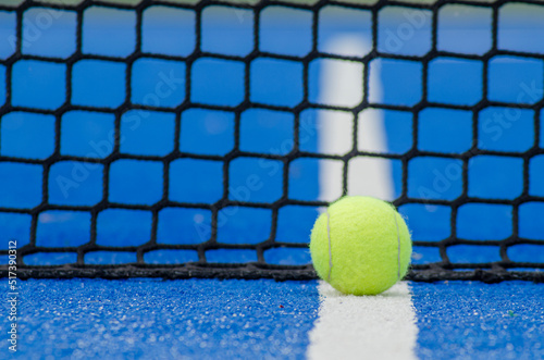 selective focus, ball on a blue paddle tennis court on the line near the net © Vic