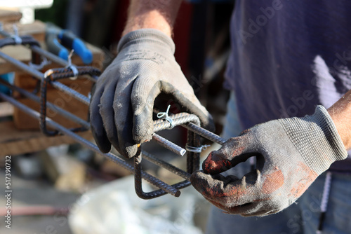 Hand holding reinforcement steel. Professional construction worker.  Close up photo of builder's hands in protective gloves.  © Maya