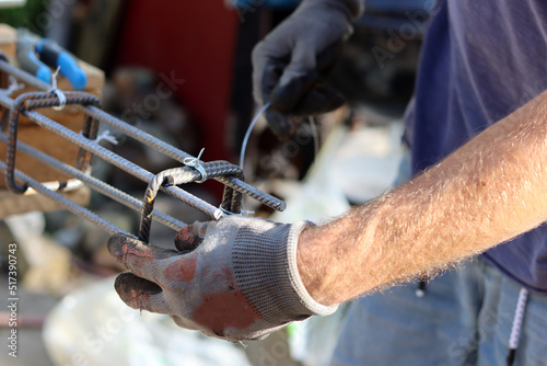 Hand holding reinforcement steel. Professional construction worker. Close up photo of builder's hands in protective gloves. 