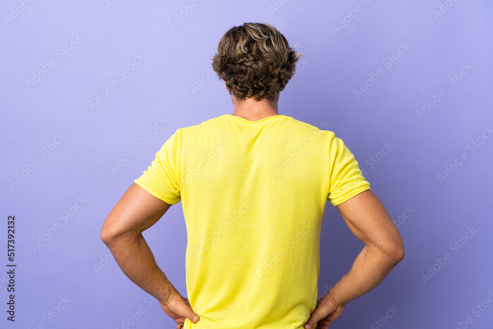 English man over isolated purple background in back position English man over isolated purple background in back position