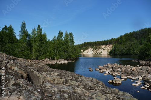 A frozen laban in the foreground and a river with a green forest in the distance. Girvas paleovolcano is a popular place among tourists. The concept of travel in Russia. photo