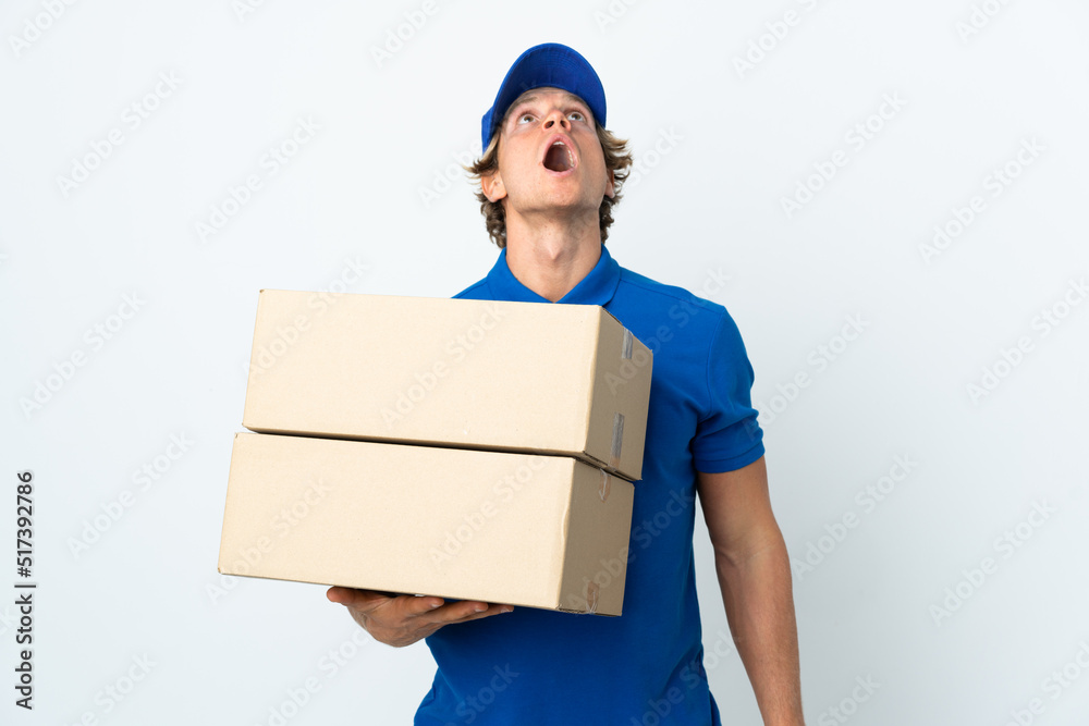 Delivery man over isolated white background looking up and with surprised expression Delivery man over isolated white background looking up and with surprised expression