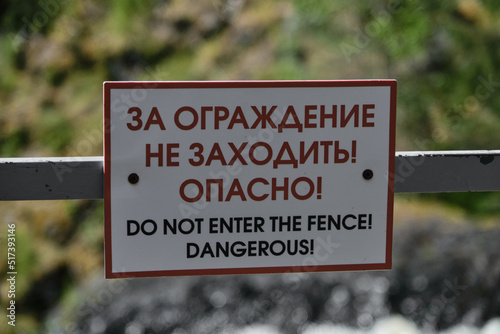 Warning sign for tourists in English and Russian means - dont go behind fence, it is dangerous for life. he concept of travel in Russia. Kivach Nature Reserve in Karelia. photo