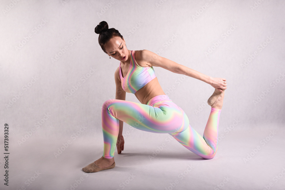 A beautiful slender gymnast in a stretch in a tracksuit does sports or yoga in the studio A beautiful slender gymnast in a stretch in a tracksuit does sports or yoga in the studio