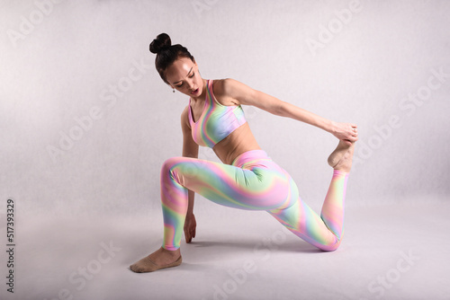 A beautiful slender gymnast in a stretch in a tracksuit does sports or yoga in the studio