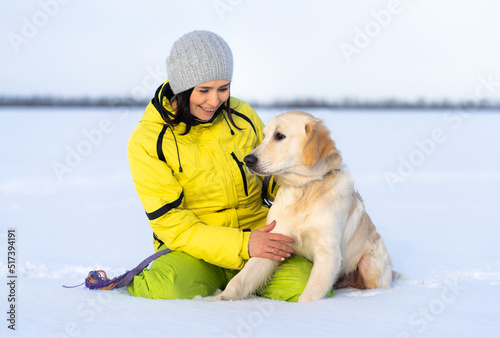 Beautiful girl with lovely young retriever dog outside in winter