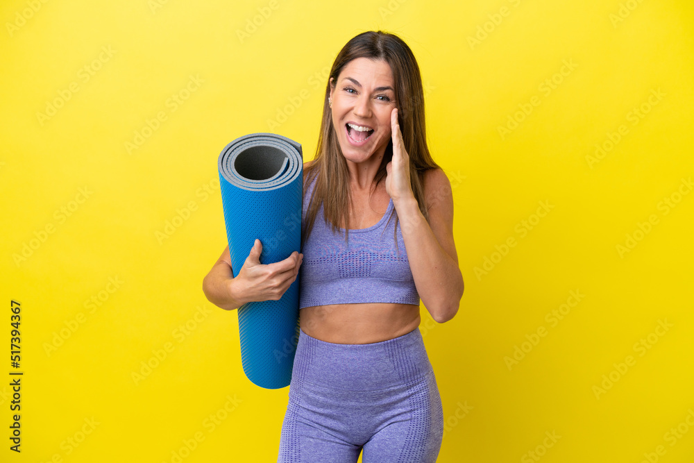 Sport woman going to yoga classes while holding a mat isolated non yellow background shouting with mouth wide open Sport woman going to yoga classes while holding a mat isolated non yellow background shouting with mouth wide open