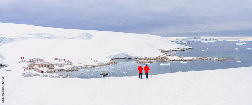 Antarktis Touristen in roten Parkas erklimmen eine antarktischer Eisberg Landschaft bei Portal Point welches am Zugang zu Charlotte Bay auf der Reclus Halbinsel, an der Westküste von Graham Land liegt
