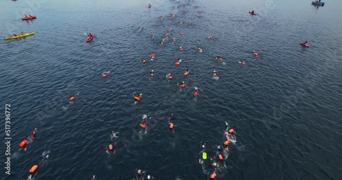 Open water swimming competitions. Swimmers with buoys. A sports event on the water. Aerial view of the swimmers during the swim. A group of people in wetsuits swim to the finish line.  photo