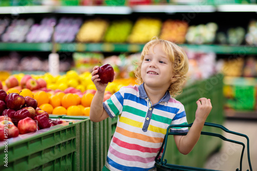 Child in supermarket. Kid grocery shopping. photo