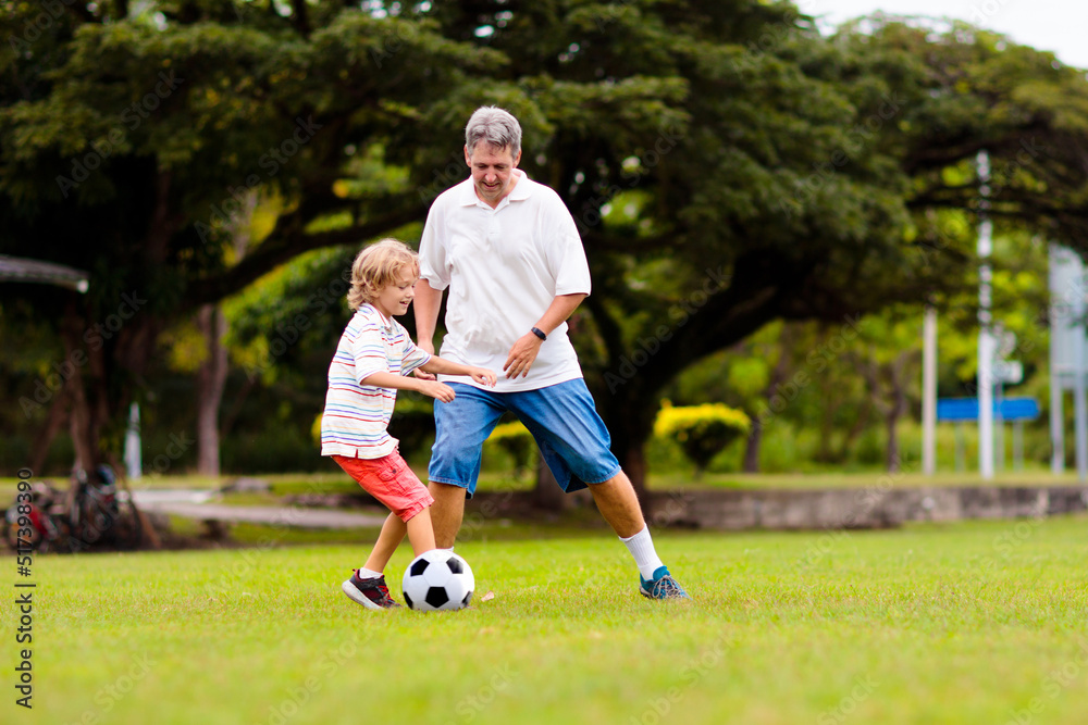 Father and son play football. Dad and kid run.