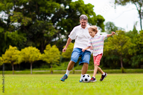 Father and son play football. Dad and kid run. © famveldman