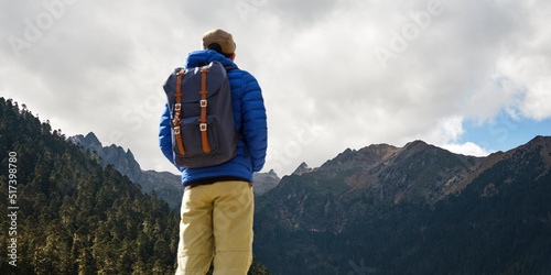 rear view of asian traveler with backpack looking at mountains