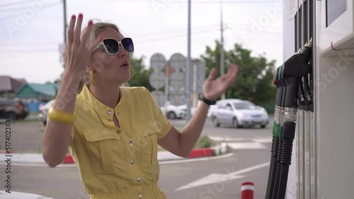A woman driver at a gas station is shocked by the rise in prices for automotive fuel. The concept of inflation and rising gasoline prices