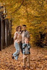 Happy family of a man with a woman holding an ultrasound pregnancy picture and a surprised son who will be the older brother. Autumn photo shoot of a family waiting to be replenished