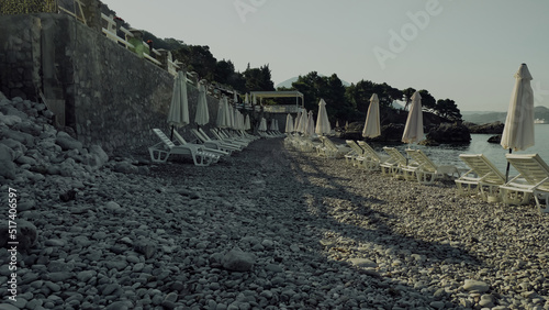 White plastic chaise-longues on the mediterranean pebble beach