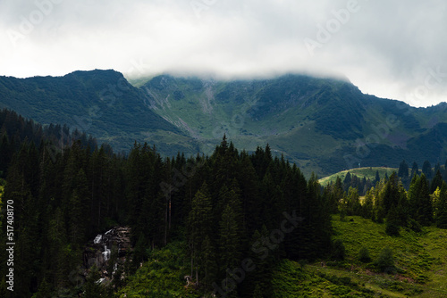 Mountain Scenery In the Alps with A Forest, A Meadow, A Waterfall And A Mountain Top In The Background