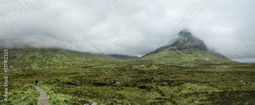 Hiking through dramatic and cloudy landscape  of Buachaille Etive Beag in the Scottish Highlands photo