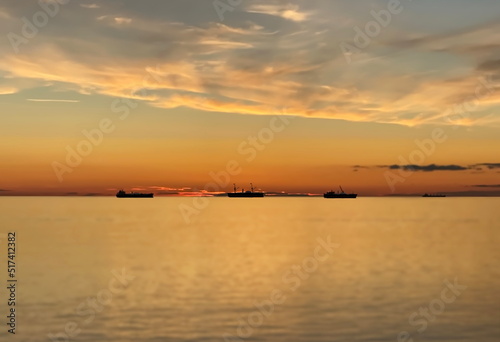 orange  gold sunset cloudy  sky at sea water reflection ship on horizon nature landscape seascape