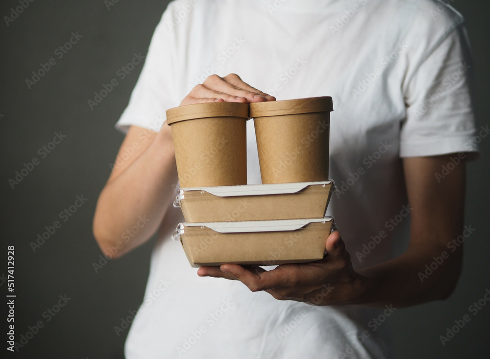 Stack of food delivery boxes in hands. Anonymous hands holding stack of food delivery packaging