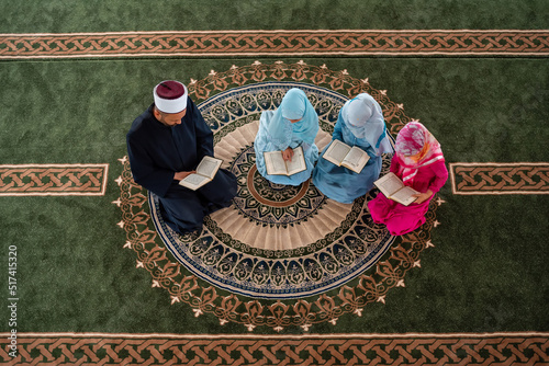 A Muslim teacher teaches a group of children girls to read a holy book Quran inside the Mosque. photo