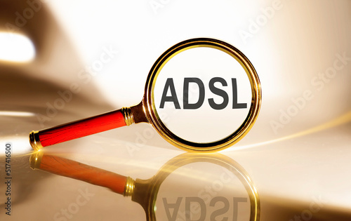 ADSL - Asymmetrical Digital Subscriber Line concept. Magnifier glass with text on white background in sunlight.