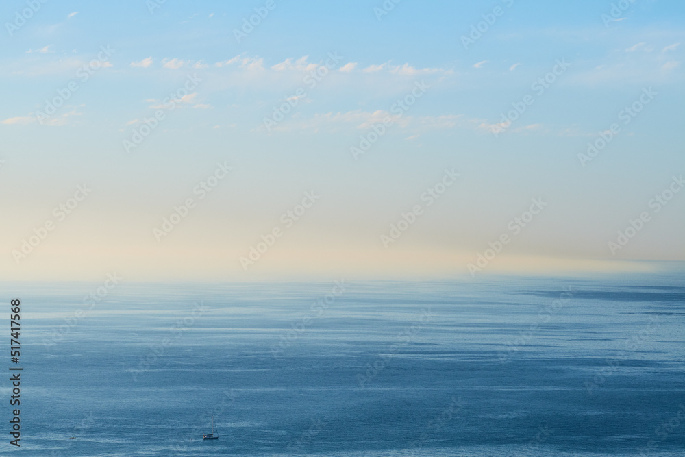 An empty ocean with a blue sky and copy space. A wide open seascape background of a beach with calm water. Scenic sea surface with calming ripples and the rising morning sun on the horizon