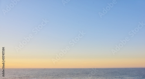 Seascape of a beautiful golden sunset with copy space. Sun setting on the horizon of a calm ocean at dusk or twilight. The calm and tranquil ocean or sea in the evening with bright sky copyspace