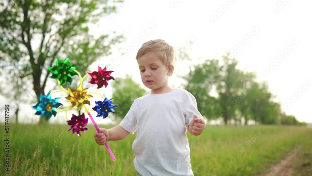 baby boy playing with spinner toy in the park. happy family kid dream concept. baby a son plays with a toy windmill outdoors in the forest in summer lifestyle baby boy playing with spinner toy in the park. happy family kid dream concept. baby a son plays with a toy windmill outdoors in the forest in summer lifestyle