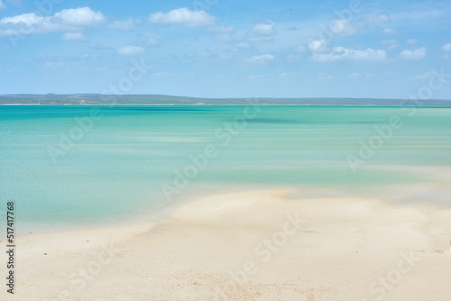 Copyspace at the sea with a blue sky and mountain background above the horizon. Calm blue ocean water at an empty beach shore. Peaceful scenic coastal landscape for a relaxing and zen summer getaway