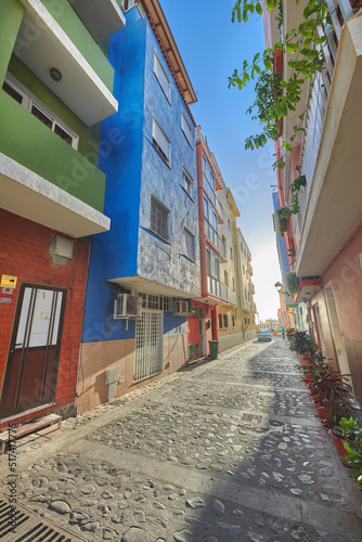 Fototapeta Naklejka Na Ścianę i Meble -  Historical city street view of residential houses in small and narrow alley or road in tropical Santa Cruz, La Palma, Spain. Village view of vibrant buildings in popular tourism destinations overseas