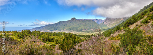Scenic landscape of mountains in La Palma, Canary Islands, Spain against a cloudy blue sky background with copyspace. Wild plants and shrubs growing on a rocky hill and cliff in natural environment