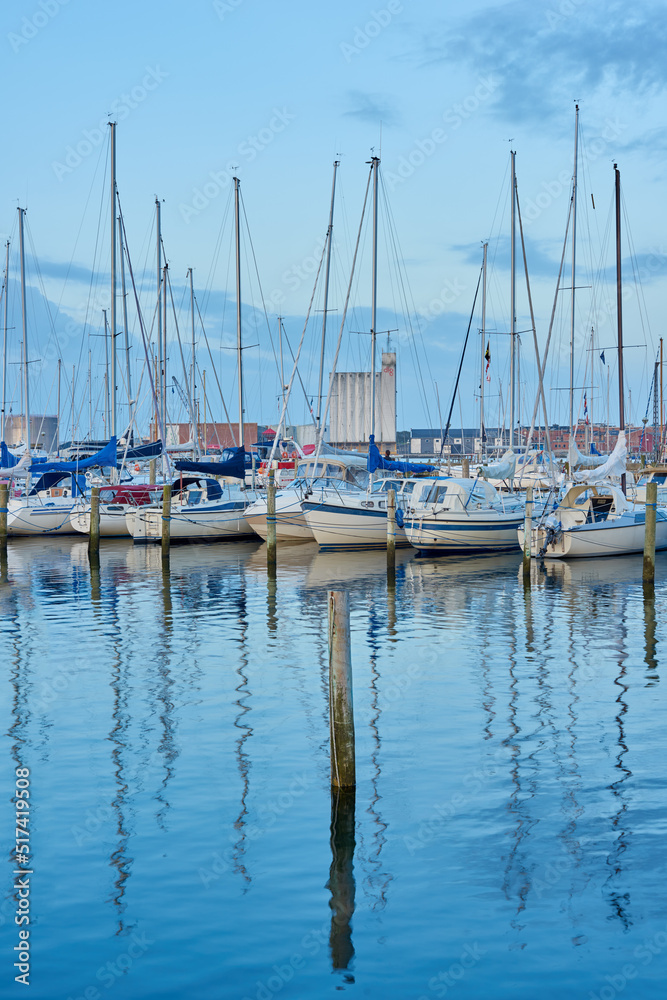 Group of boats docked in a harbor of Bodo. Scenic view of sailing yachts in cruise port and bay at dusk. Rippled water and sky in oceanside port for fishing or traveling abroad for vacation