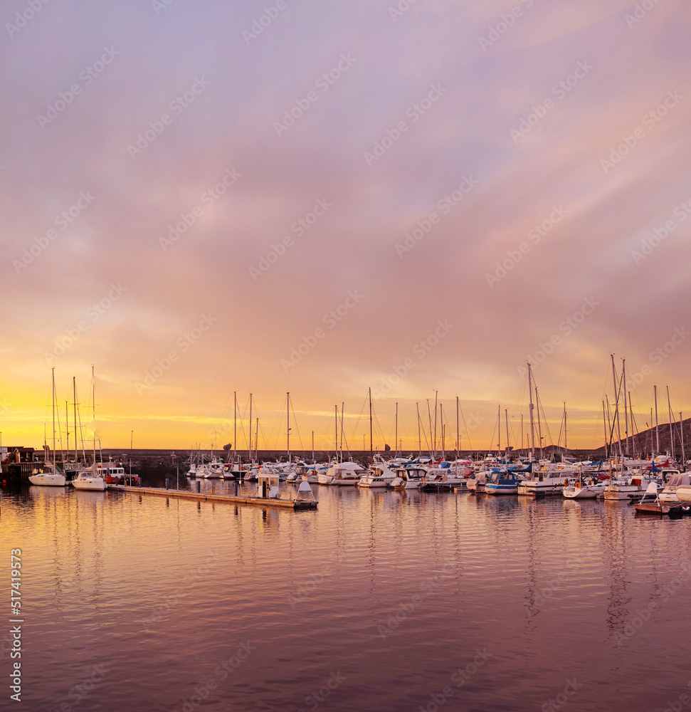 Scenic view of private yachts docked in water harbor at sunset in Bodo, Norway. Nautical transport vessels and boats in a dockyard in the morning at dawn before sailing on the ocean, sea or lake