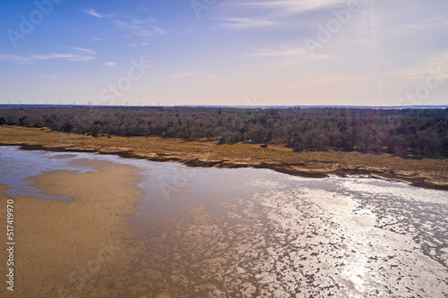 Dry bush land by the beach with clear sky copy space. Landscape of the mudflat with calm water surface reflection on a sunny day. A peaceful aerial view of Mariager Fjord flow in Jutland