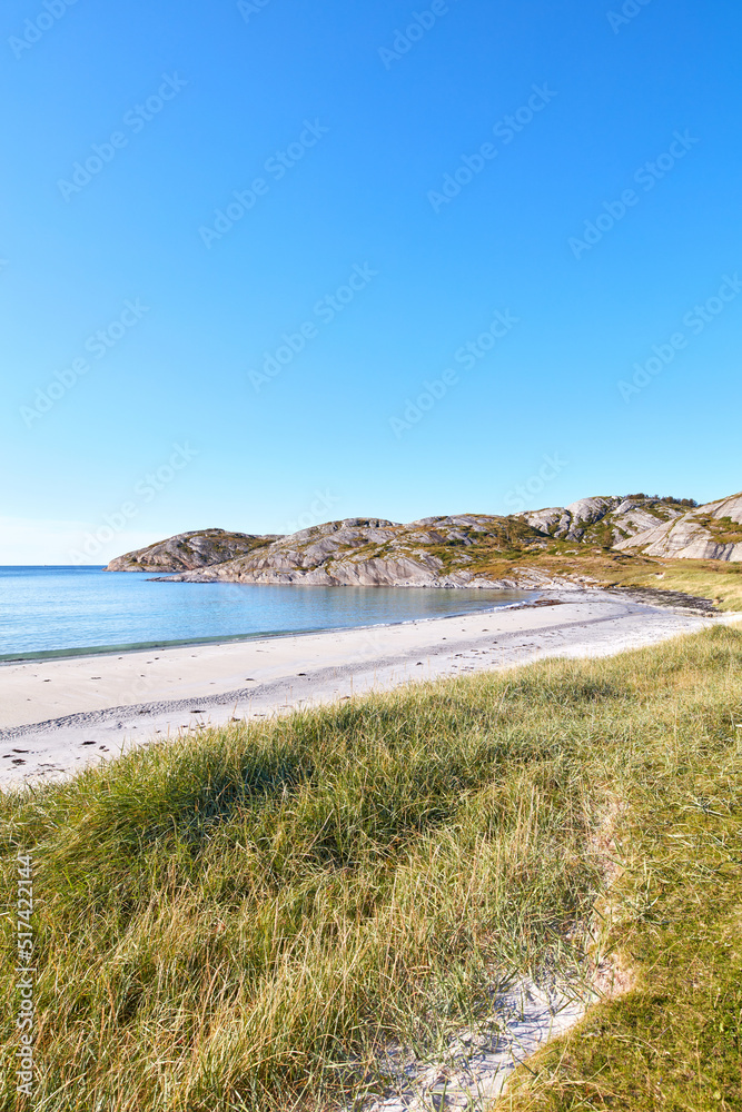 Copyspace at the beach with blue sky background above the horizon. Calm ocean waves across an empty sea along the shore with a grassy meadow. A tranquil landscape for a relaxing summer holiday Copyspace at the beach with blue sky background above the horizon. Calm ocean waves across an empty sea along the shore with a grassy meadow. A tranquil landscape for a relaxing summer holiday