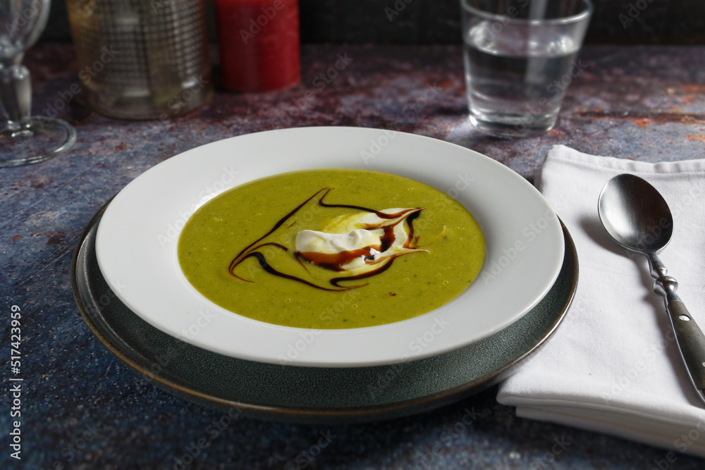 Potato soup with pureed lamb's lettuce, served in white plate