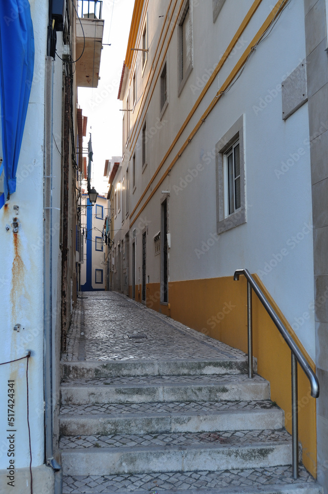 Rua típica de Portugal da zona centro do país, com escadas no inicio da rua e paredes pintadas com riscas